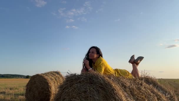 4k Χαμογελώντας κορίτσι σε κίτρινο φόρεμα χαλαρώνοντας στα άχυρα. — Αρχείο Βίντεο