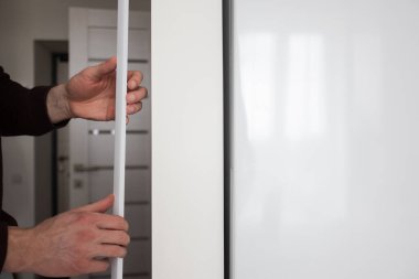 Adamın biri apartmanın duvarına koruyucu dekoratif köşe kuruyor..