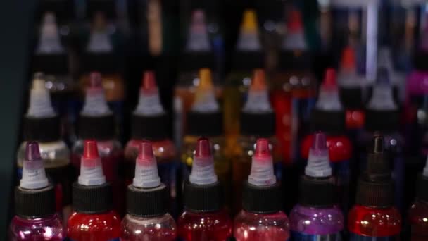 Palette of multicolour tattoo inks in small bottles. Selective focus, blurred. — Stockvideo