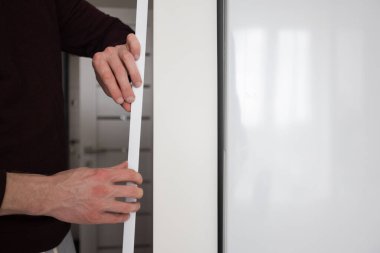 Adamın biri apartmanın duvarına koruyucu dekoratif köşe kuruyor..