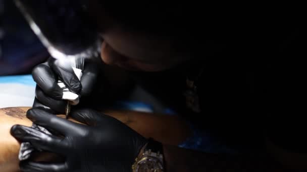 Tattoo kunstenaar is geconcentreerd op het zetten van tatoeage. — Stockvideo