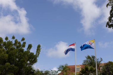 Bonaire ve Hollanda bayrağı mavi gökyüzü arka planında rüzgarda dalgalanıyor.