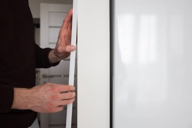 Adam apartmanın duvarına koruyucu plastik bir köşe yapıştırıyor..