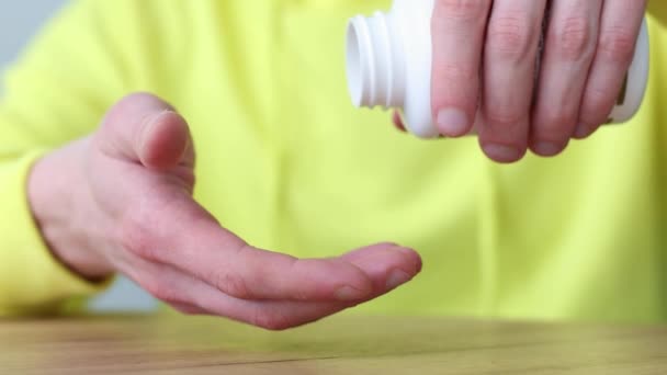 Facet bierze witaminy z butelki po tabletkach. Zbliżenie. Opieka zdrowotna i medycyna. — Wideo stockowe