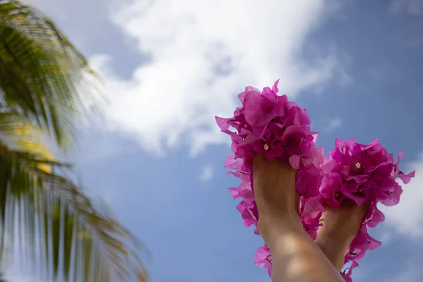 Женские ноги в туфлях из розовых свежих цветов на голубом фоне неба — стоковое фото