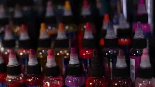 Palette of multicolour tattoo inks in small bottles. Selective focus, blurred. — Stock Video