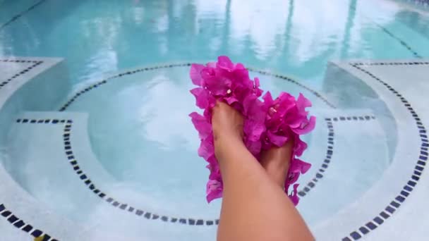 Damskie stopy w butach z różowych świeżych kwiatów w pobliżu basenu. — Wideo stockowe