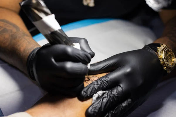 Mãos de tatuador em luvas pretas ocupadas com trabalho. — Fotografia de Stock
