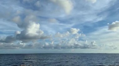Time Lapse of white fluffy clouds flying over the sea.