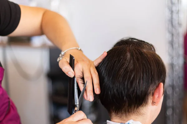 Taglio di capelli a parrucchiere. Trattare i capelli al salone di bellezza. Primo piano. — Foto Stock