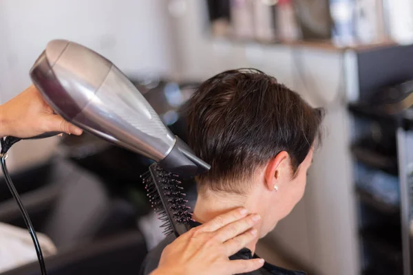 Parrucchiere asciugatura capelli donna in salone parrucchiere. — Foto Stock