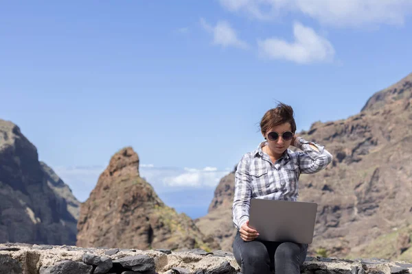 Young woman with laptop working between mountains