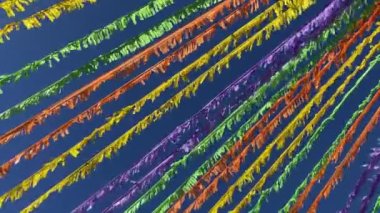 Mavi gökyüzünün önündeki caddeyi süsleyen çok renkli kurdeleler. 4k görüntü