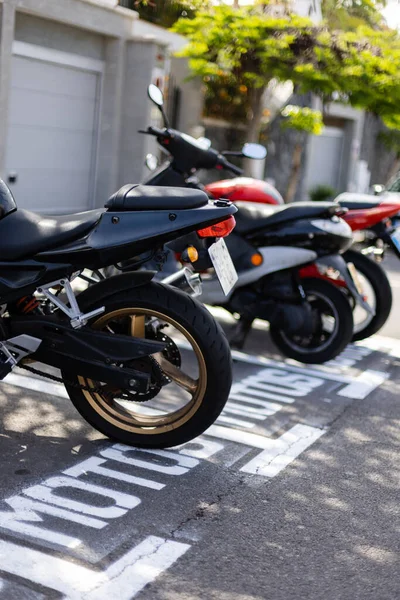 Motorbikes parked on a parking lot outside. Sign on the road