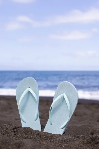 一双夏鞋放在海滩上 由黑色的沙子做成 暑假的概念 — 图库照片