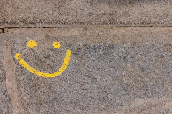Yellow smiley face on a stone wall. Natural background