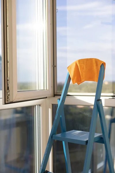 公寓的全景窗户附近 蓝色梯子上的橙色破布 鸡舍观念 免版税图库图片