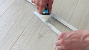 Mans elleri apartmanın duvar koruması için dekoratif plastik köşelere yapıştırıcı sürüyor. 4k görüntü.