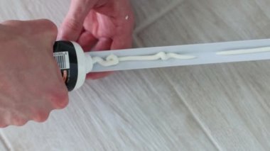 Mans elleri apartmanın duvar koruması için dekoratif plastik köşelere yapıştırıcı sürüyor. 4k görüntü.
