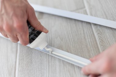 Mans elleri plastik inşaat detaylarına yapıştırıcıyı tüpten çıkarıyor. - Yakın çekim. Evde tamir ediliyor..