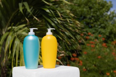 Blue and yellow sunscreen bottles on palm leaves background. Mockup. 