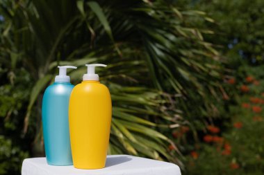 Blue and yellow sunscreen bottles on palm leaves background. Mockup. 