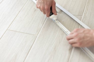 Mans hands putting glue out of tube to plastic construction detail