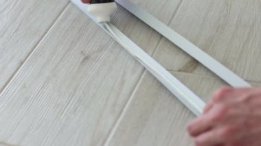 Mans elleri apartmanın duvar koruması için dekoratif plastik köşelere yapıştırıcı sürüyor. 4k görüntü.