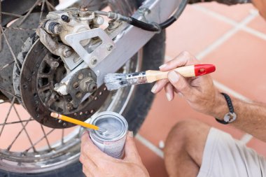 Man painting his motorbike with brush at home. Renew old motorbike.