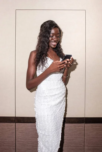 Een Glimlachende Zwarte Jonge Vrouw Die Haar Telefoon Gebruikt Droeg — Stockfoto