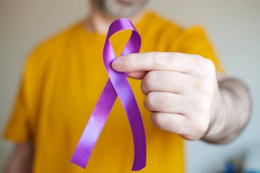 Sol kolunda mor bir kurdele var. Epilepsi, pankreas kanseri ve Alzheimer sembolü.