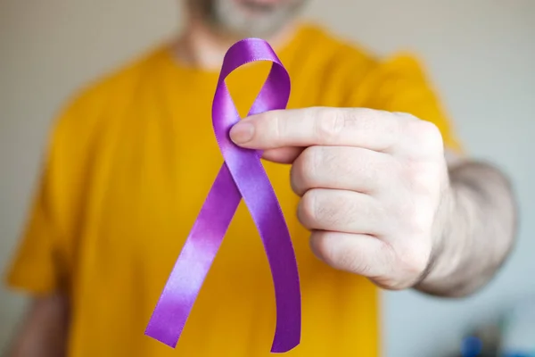 Sol kolunda mor bir kurdele var. Epilepsi, pankreas kanseri ve Alzheimer sembolü.