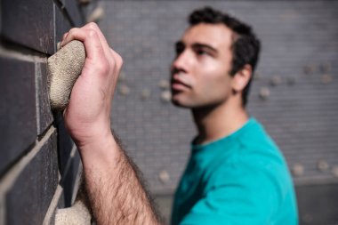 Genç bir adam şehirde balık avlıyor. El odakta, yüz odakta değil. O bir karşılama tişörtü giyiyor..