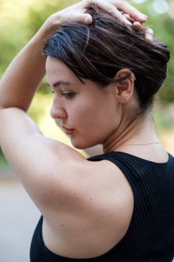 Kafkasyalı genç bir kadın yoga yapmaya ara verirken poz veriyor. Siyah bir atlet giyiyor..