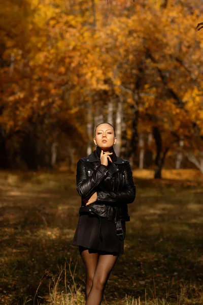 Seasonal autumn fashion. Modern young woman wearing fashionable warm clothes posing in the autumn park.