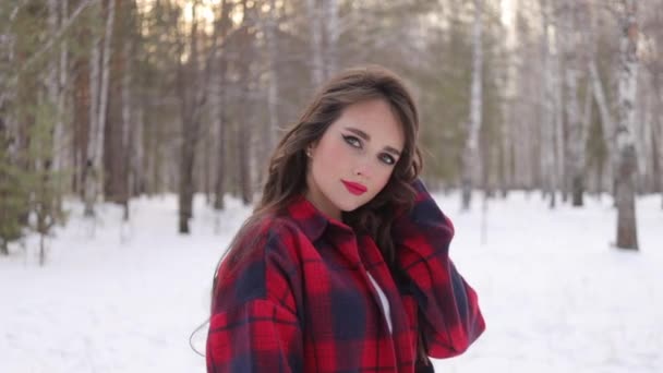 Jovem com cabelo ondulado em pé e rosto tocante na floresta de inverno — Vídeo de Stock