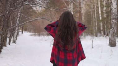 Karlı parkta karlı gömlekli bir kadın yürüyor.