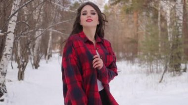 Karlı parkta karlı gömlekli bir kadın yürüyor.