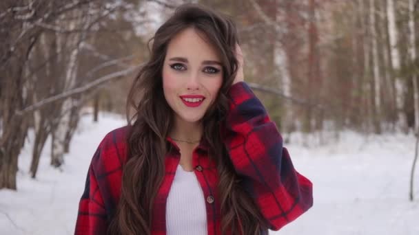 Giovane donna con capelli ondulati in piedi e faccia toccante nella foresta invernale — Video Stock