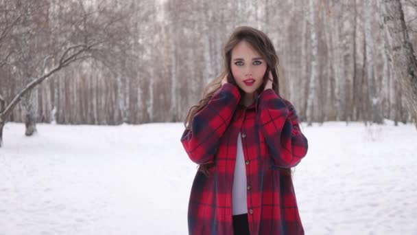 Молодая женщина с волнистыми волосами, стоящая и трогательное лицо в зимнем лесу — стоковое видео