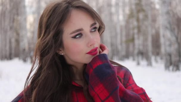 Jonge vrouw met golvend haar staande en ontroerende gezicht in de winter bos — Stockvideo