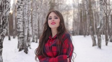 Karlı ormanda yürüyen uzun saçlı çekici bir kadın.