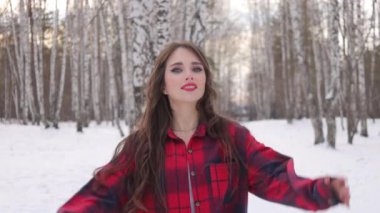 Karlı ormanda yürüyen uzun saçlı çekici bir kadın.