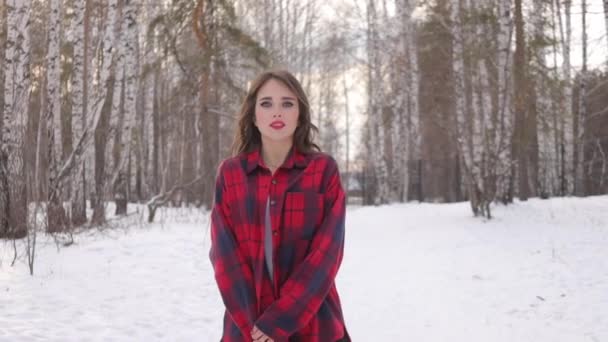 Charmant vrouwtje met lang haar wandelen in besneeuwd bos — Stockvideo