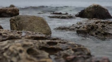 Wet stony coast washed by rippling sea