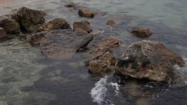 Wet stony coast washed by rippling sea