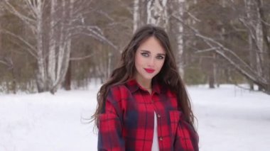 Karlı ormanda yürüyen uzun saçlı çekici bir kadın.