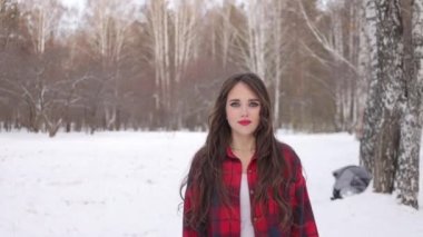 Karlı ormanda yürüyen uzun saçlı çekici bir kadın.