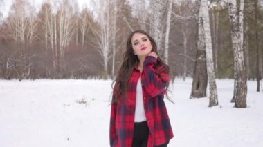 Karlı ormanda yürüyen uzun saçlı çekici bir kadın.