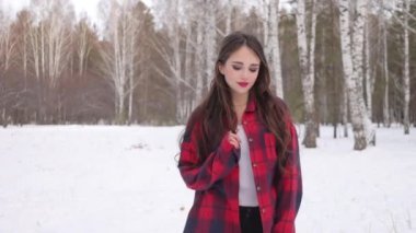 Karlı ormanda yürüyen uzun saçlı çekici bir kadın.